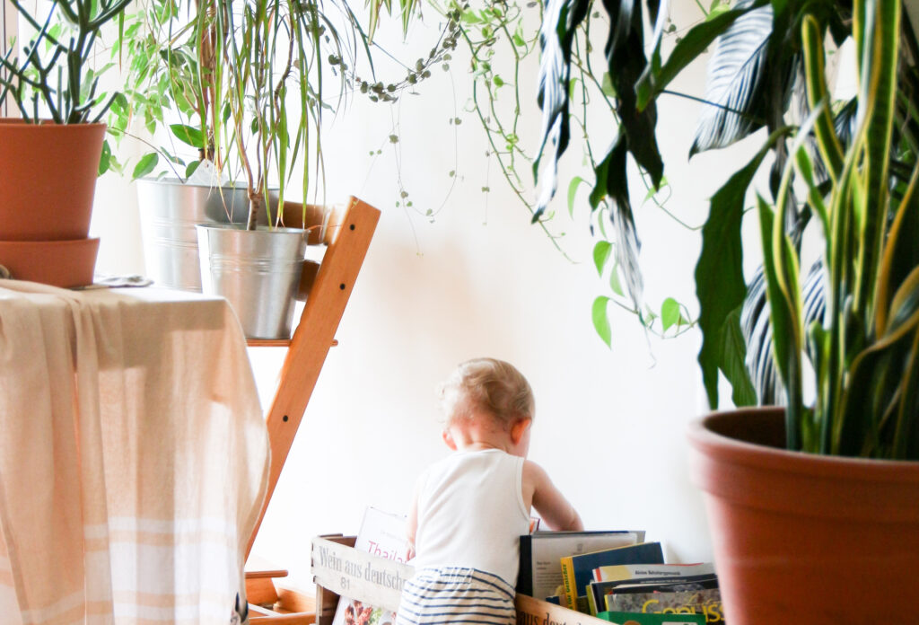 Baby surrounded by plants - The Best Ways to Baby Proof Your Plants